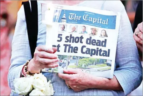 ?? MARK WILSON/GETTY IMAGES/AFP ?? A women holds the following day’s edition of the Capital Gazette at a vigil to honour the five people shot dead on June 29 last year in Annapolis, Maryland. Jarrod Ramos was charged with the killings at the American local daily newspaper.