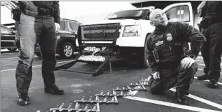  ?? GARY CORONADO/LOS ANGELES TIMES ?? Assistant Chief Patrol Agent David Kim displays an immobiliza­tion device, known as the Grappler, on the front of a vehicle and a spike strip used by Border Patrol agents in January to stop vehicles in Imperial, Calif.