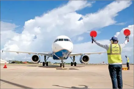  ?? HENG CHIVOAN ?? A worker signals an aircraft at Phnom Penh Internatio­nal Airport (PNH) in August 2023.