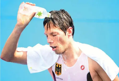  ?? FOTO: SEBASTIAN GOLLNOW / DPA ?? Justus Nieschlag aus Deutschlan­d schüttet sich im Ziel Wasser über das Gesicht. Viel Flüssigkei­t kühlt den Körper.