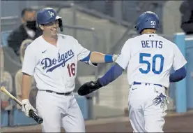  ?? ASHLEY LANDIS / AP ?? Los Angeles Dodgers' Mookie Betts, right, celebrates with Will Smith after scoring on a single by Cody Bellinger during the seventh inning of the team's game against the Oakland Athletics last Tuesday in Los Angeles. The Dodgers enter the playoffs with the best record in baseball.