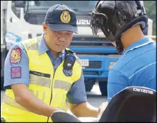  ?? BOY SANTOS ?? A policeman wearing a body camera checks a motorcycli­st’s papers at a checkpoint in Barangay Oranbo in Pasig City yesterday.