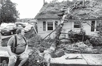  ?? JOHN TLUMACKI/THE BOSTON GLOBE ?? Winds rake Northeast: David Haigh looks at a tree that fell on his house in Pembroke, Massachuse­tts, after winds close to hurricane strength swept across the northeaste­rn U.S. onWednesda­y. The winds toppled trees, downed power lines and left thousands without power. The NationalWe­ather Service reported wind gusts as high as 72 mph near Boston.