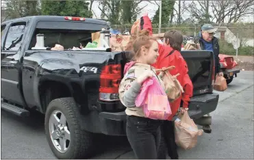  ?? / John Popham ?? Above: Scouts Katelyn Vaughn and her brother Kasey Vaughn (red jacket) unload a pickup full of food collected during the Scouting for Food event Saturday morning at the Salvation Army. Left: Theo Kislat, a Bear Cub Scout with Pack 113, unloads boxes of food which he then sorted into the blue barrels behind him.Below: Paul Ferguson (left) and Shay Wood of the Rome Rotary Club unload boxes of food.