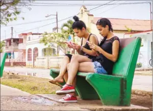  ?? ADALBERTO ROQUE/AFP ?? Young Cubans use Wi-Fi on their cellphones at a park in Gaspar, a small town in Ciego de Avila province in central Cuba, on April 18.