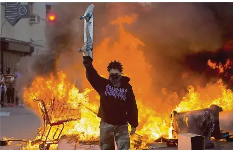  ?? FOTO: RINGO H.W. CHIU/DPA ?? Anarchie bei Protesten auch in der US-Metropole Los Angeles: hier ein Flammen-Inferno hinter einem maskierten Demonstran­ten.