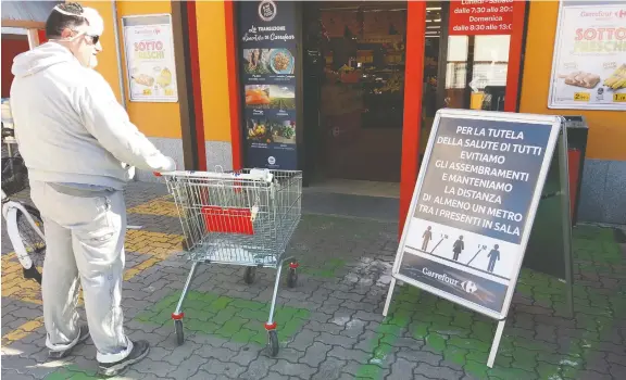  ?? PHOTOS: JAKE RUPERT ?? A shopper looks at the warning signs on social distancing outside a grocer in Torre de’passeri, Italy, which former Ottawan Jake Rupert describes as a ghost town.