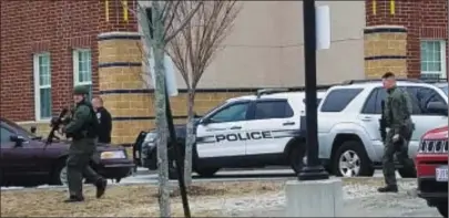  ?? Photo by Joseph B. Nadeau ?? Woonsocket Police officers in SWAT gear patrol the campus of Hamlet Middle School on Friday afternoon. A lockdown and police response was prompted by two incidents – a discovery of several rounds of ammunition in a bathroom, and a student who started...