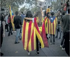  ?? SANTI PALACIOS/THE ASSOCIATED PRESS ?? Two girls, one with a Catalan independen­ce flag wrapped on her shoulders walks together with another one with a Spanish flag as demonstrat­ors gather in downtown Barcelona, Spain.