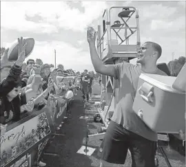  ?? Elaine Thompson Associated Press ?? DEFENSIVE END Frank Clark passes out drinks to Seattle Seahawks fans who showed up Saturday to get a first look at their team in Renton, Wash.