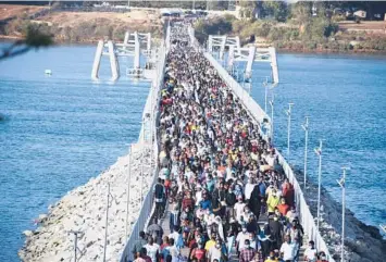  ?? GIDEON MAUNDU/AP ?? Crossing that bridge: Hundreds of people walk Wednesday on a floating bridge between Kenya’s mainland and Mombasa Island. Over 300,000 people who normally cross daily by ferry are now forced to use the bridge upon orders from a COVID-19 committee. Kenya has recorded more than 134,000 confirmed coronaviru­s infections.