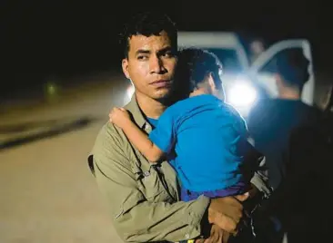  ?? GREGORY BULL/AP ?? A Peruvian migrant holds his son as he waits to be processed Aug. 23 by Border Patrol agents near Yuma, Ariz.