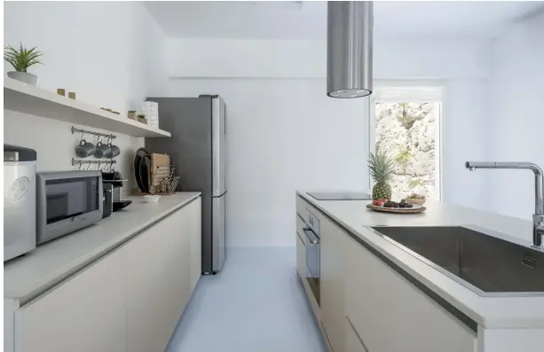  ??  ?? A SINISTRA, IL LIVING CON DIVANI BIANCHI E UNA PARETE IN BOISERIE CHE INTEGRA LA TV. A DESTRA, LA CUCINA DI MODULNOVA CON IL TOP IN CORIAN.
LEFT: THE LIVING ROOM WITH WHITE SOFAS AND WALL PANELLING THAT HOUSES THE TV. RIGHT: THE MODULNOVA KITCHEN WITH CORIAN WORKTOP.