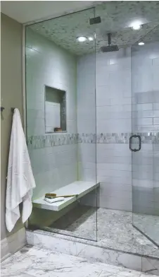  ??  ?? A shower with a rain shower head, bench and wall niche is a focal point of this bathroom by Kate + Co Design Inc.