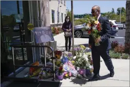 ?? ASHLEY LANDIS — THE ASSOCIATED PRESS ?? A man places flowers at a memorial honoring Dr. John Cheng outside his office building Tuesday in Aliso Viejo. Cheng, 52, was killed in Sunday's shooting at Geneva Presbyteri­an Church.