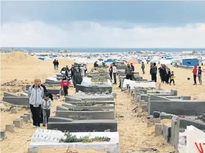  ?? - / AFP ?? Gazatíes, en un cementerio en Rafah durante el Eid el Fitr; al fondo, las tiendas de los refugiados
