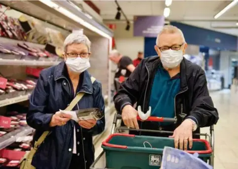  ?? FOTO BOUMEDIENE BELBACHIR ?? Dit koppel gaf vrijdag al het goede voorbeeld bij het winkelen in de Delhaize in Hasselt. De meeste supermarkt­en verwachten weinig problemen nu het mondmasker vanaf dit weekend verplicht wordt.