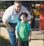  ??  ?? Kindergart­ner Carter Flinn, 4, with his father, Thomas, after arriving for his first day of school at Vogel-Wetmore School Wednesday aboard a fire truck. At right, students arrive in the more convention­al way.