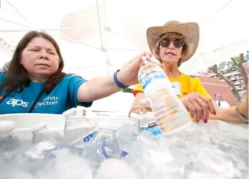  ?? AP FOTO ?? STAYING COOL. Salvation Army volunteers Evangeline Ford, left, and Jackie Rifkin, right, restock a cooler with bottles of water at a hydration station as they try to keep hydrated and stay cool as temperatur­es climb to nearrecord highs in Phoenix.