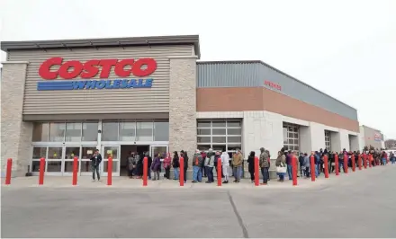  ?? PHOTOS BY MIKE DE SISTI / MILWAUKEE JOURNAL SENTINEL ?? Hundreds of people line up waiting for doors to open at Costco in Menomonee Falls on Saturday. The store was limiting customers to one 30-pack case of toilet paper.