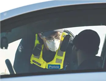  ?? AAP / James Ross ?? A Victorian police officer questions a driver at a vehicle checkpoint.