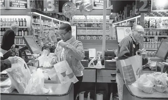  ?? KARL MERTON FERRON/BALTIMORE SUN ?? Cashiers Sharanda Randolph and Lester Watson bag groceries for customers at the Ruxton Graul's Market in April.