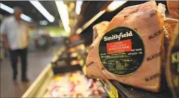  ?? LM Otero Associated Press ?? SMITHFIELD, which is owned by Chinese conglomera­te WH Group, will sell 144,000 pounds of ham products to the federal government under the contract. Above, a ham at a grocery store in Richardson, Texas, in 2011.