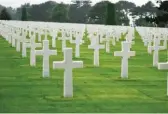  ??  ?? Plus de 9000 croix blanches se dressent sur la pelouse du cimetière de Colleville.
La traversée des bourgs est jalonnée des portraits de soldats du D-Day.