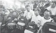  ?? — Gambar Bernama ?? TERIMA KASIH: Muhammad Faiz (belakang,tiga kanan) beramah mesra dengan sebahagian murid yang menerima sumbangan pakaian sekolah pada Program Kembali Ke Sekolah Anak-Anak Nelayan Dewan Undangan Negeri (DUN) Beserah di Sekolah Kebangsaan Chengal Lempong, semalam.