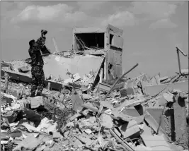  ?? ASSOCIATED PRESS ?? A SYRIAN SOLDIER FILMS the damage of the Syrian Scientific Research Center which was attacked by U.S., British and French military strikes to punish President Bashar Assad for suspected chemical attack against civilians, in Barzeh, near Damascus,...