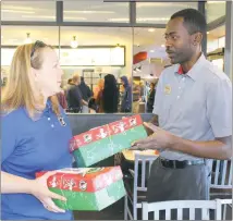  ??  ?? Flavio Ingles, a Chick-fil-a employee, hands two shoeboxes to Melissa Weikel, Southern Maryland network coordinato­r for Operation Christmas Child. The boxes contain items for children living overseas.