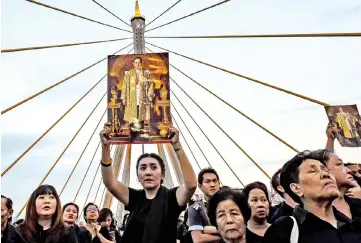  ?? — AFP photo ?? File photo shows a woman holding aloft a picture of the late King Bhumibol as people gather to commemorat­e his birthday on top of Bhumibol Bridge in Bangkok.