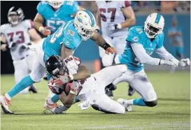  ?? PHELAN M. EBENHACK/AP ?? Atlanta’s Devonta Freeman, center, is stopped by Miami linebacker Jelani Jenkins, left, and defensive back Byron Maxwell on Thursday in Orlando.