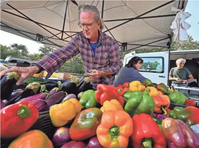  ?? PHOTOS BY ALLAN JUNG/TELEGRAM & GAZETTE ?? Mark Lyn and Paula Harper of Harperss Farm and Garden of Lancaster add more produce to their stand at the REC Community Farmers Market at Beaver Brook Park on Friday.