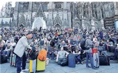  ?? FOTO: REUTERS ?? Viele Bahnreisen­de harrten mit ihrem Gepäck auf der Domplatte nahe des Hauptbahnh­ofs aus.