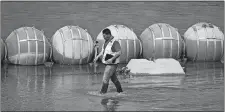  ?? ERIC GAY/AP PHOTO ?? A worker inspects buoys being used as a barrier Monday along the Rio Grande in Eagle Pass, Texas.