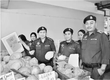  ??  ?? Kasim shows the pink price tag for imported round cabbage. On his left is Ganda.