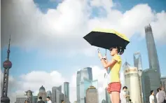  ??  ?? A woman takes a ‘selfie’ at the Bund promenade before the skyline of the Lujiazui Financial District in Shanghai. A key measure of Chinese manufactur­ing activity hit an 18-month high in July, HSBC said yesterday, in a further sign the world’s...
