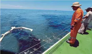  ??  ?? (Left) The oil slick found on a beach in Tanjung Balau, Kota Tinggi, yesterday. (Right) The crew of ‘Al Nilam’, a boat belonging to the Marine Department, deploying a net to clean up an oil slick yesterday.