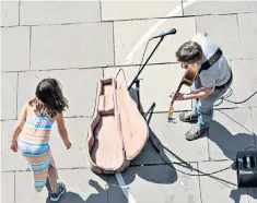  ??  ?? Streets alive with the sound of music: a busker finds a fan in pre-covid London