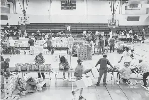  ??  ?? Volunteers pack food for families in need at John F. Kennedy Recreation Center in Newark, N. J., where people of color have been hit hard by the pandemic.