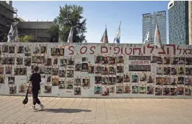  ?? HANNAH MCKAY/REUTERS ?? A child walks past posters with pictures of hostages kidnapped in the deadly Oct. 7 attack on Israel by the Palestinia­n Islamist group Hamas on Thursday in Tel Aviv, Israel.