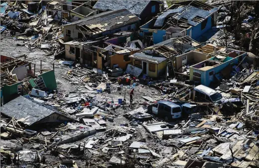  ?? CAROLYN VAN HOUTEN / WASHINGTON POST ?? A man goes through debris from Hurricane Dorian in the Mudd and Peas neighborho­ods recently in Marsh Harbour on Great Abaco Island in the Bahamas. The Mudd was built with abandoned constructi­on materials on low-lying, flood-prone ground, ravaged periodical­ly by fires.