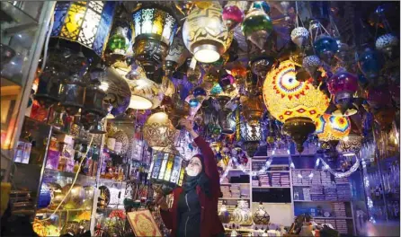  ??  ?? A Palestinia­n woman hangs decorative lights in preparatio­n for the holy Muslim month of Ramadan, at a shop in Jerusalem’s Old City, April 12. (AP)