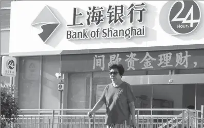  ?? ZHEN HUAI / FOR CHINA DAILY ?? A customer walks out of a Bank of Shanghai branch in Nanjing, Jiangsu province.