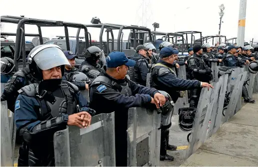  ?? AP ?? Mexican Federal Police in riot gear stand guard outside a migrant shelter for Central American immigrants in Piedras Negras.