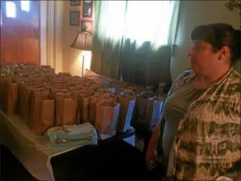  ?? KATHLEEN E. CAREY — DIGITAL FIRST MEDIA ?? Maureen Kelly Kilmartin Carreno looks over the 100 bagged meals lined in her Glenolden home.