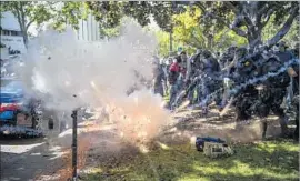  ?? David Butow For The Times ?? A FIREWORK explodes near police during a clash between counter-protesters and attendees of a pro-President Trump rally in Berkeley in April.