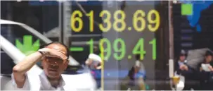  ?? (Toru Hanai/Reuters) ?? THE REFLECTION of a man is seen on an electronic board showing the London FTSE 100 index outside a brokerage in Tokyo.