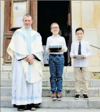  ??  ?? Le Père James et les communiant­s : Cyprien (au milieu) et Corentin.